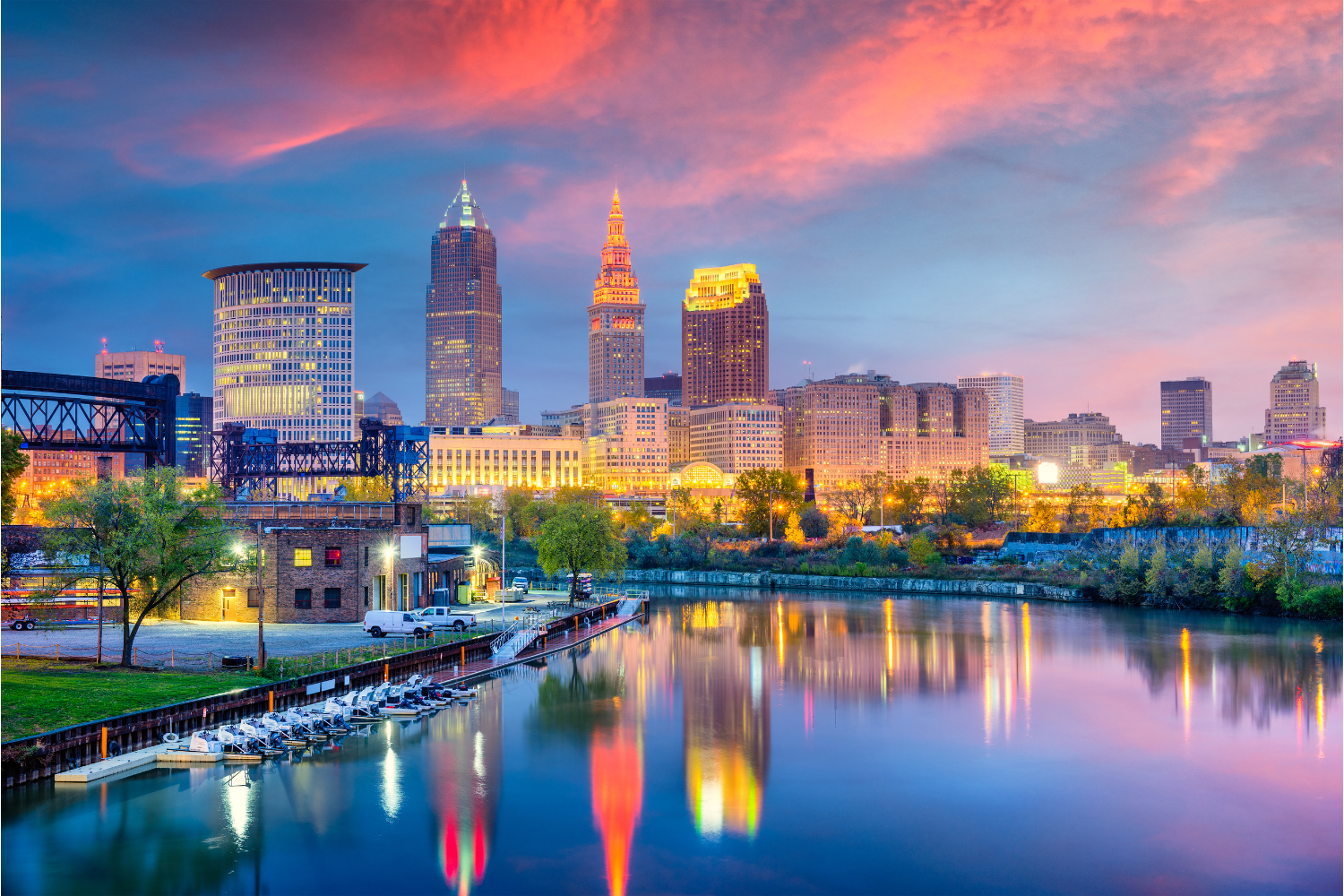 Cleveland skyline at dusk with illuminated buildings, reflecting in the Cuyahoga River, showcasing the city's vibrant atmosphere and growth potential.