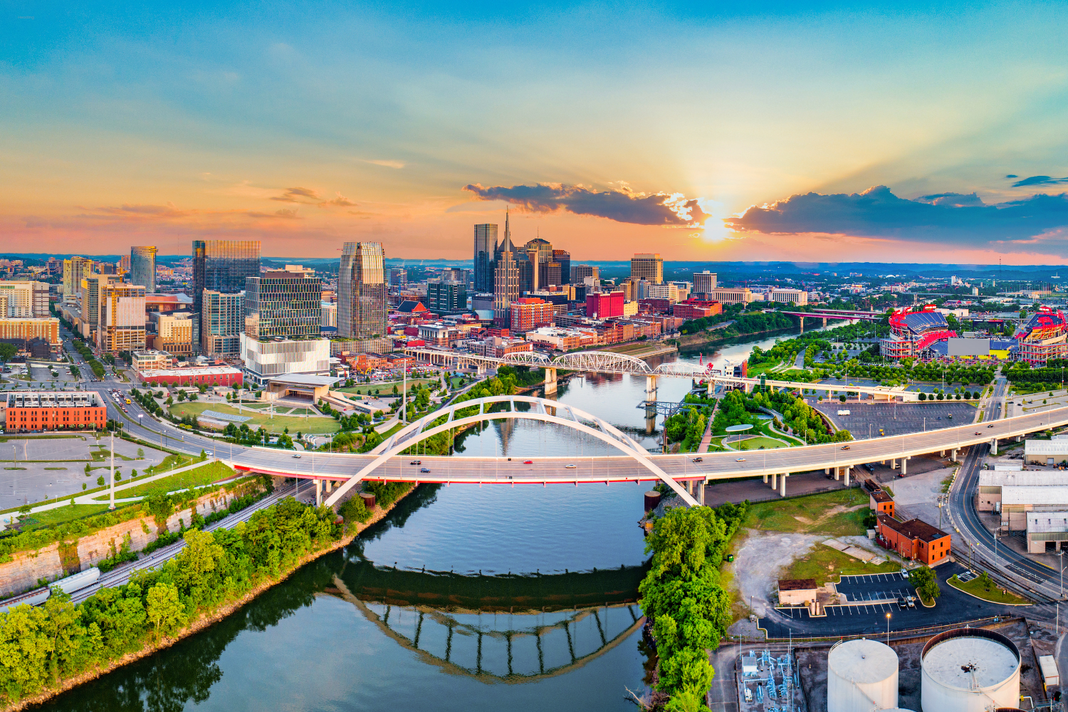 Aerial view of Nashville skyline at sunset, featuring the iconic arch bridge over the river, vibrant city buildings, and lush greenery, representing Solitude Marketing's local expertise in digital marketing services.