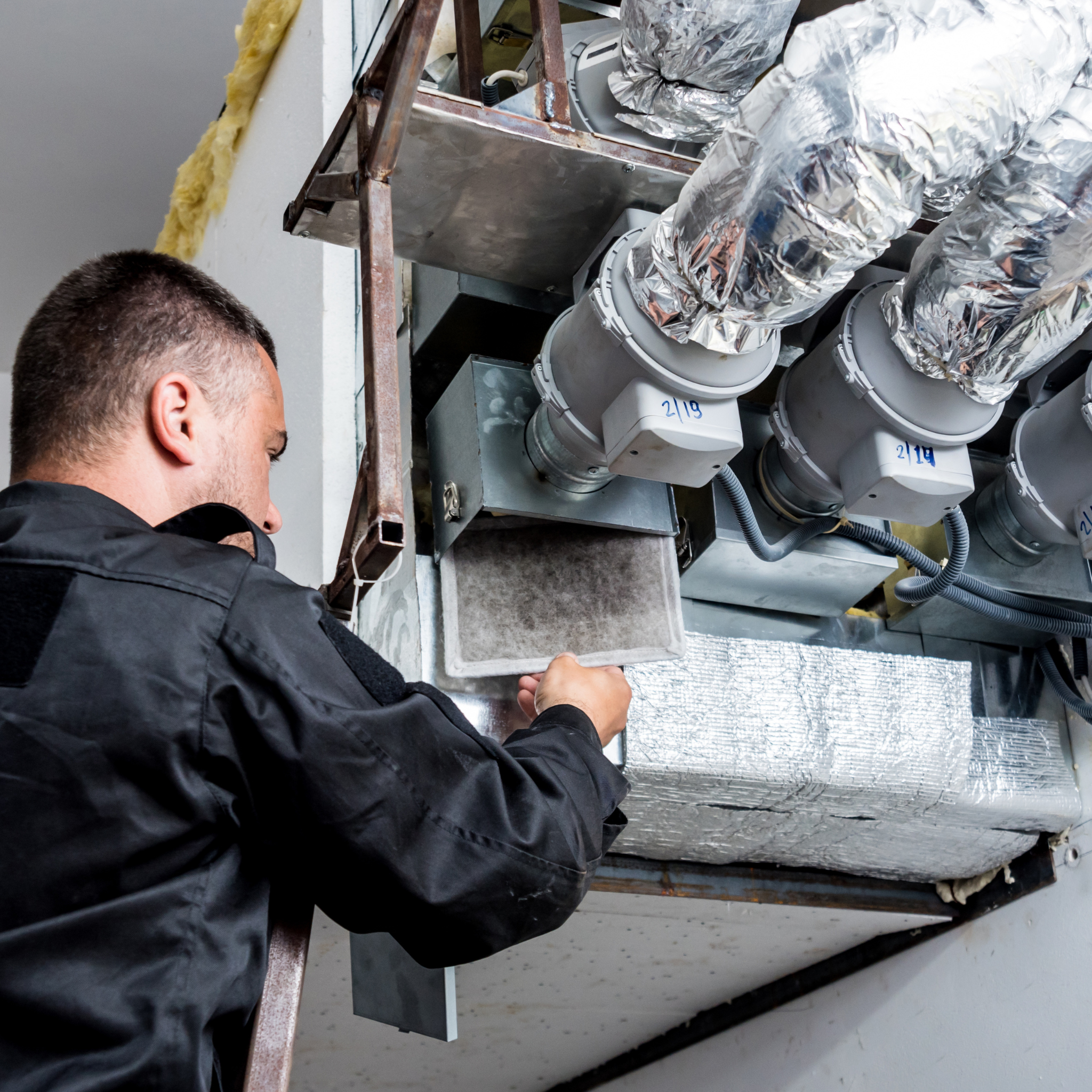 HVAC technician servicing air ducts and filters in a residential setting, showcasing professional maintenance and repair work.