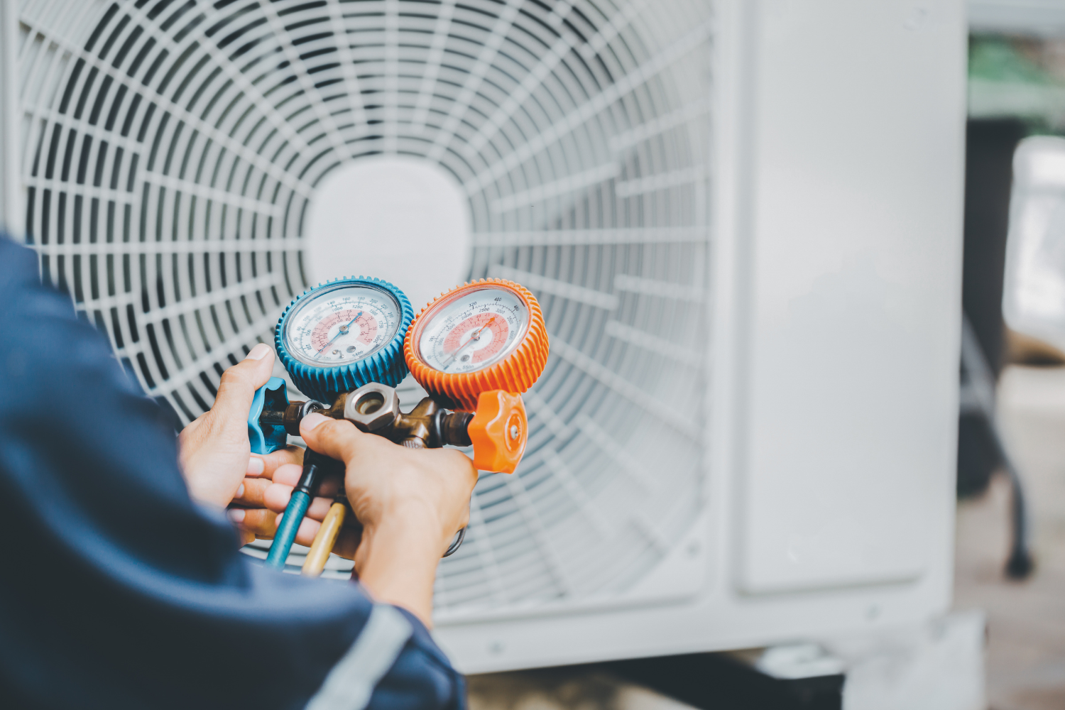 HVAC technician using gauges to check air conditioning system pressure near outdoor unit, emphasizing professional maintenance services for HVAC businesses.