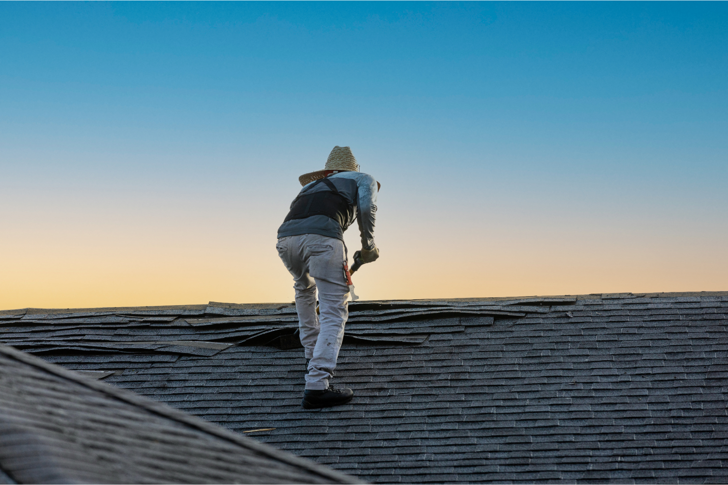 Roofer working on a sloped roof, focusing on installation or repair, with a clear sky at sunset, illustrating time management in roofing business operations.