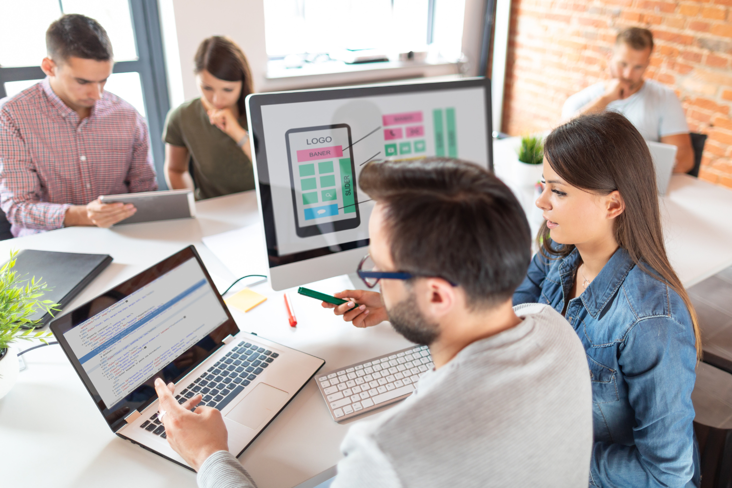 Team collaborating on digital marketing strategies, analyzing website design on computer screen, showcasing logo and layout elements for effective restaurant marketing.