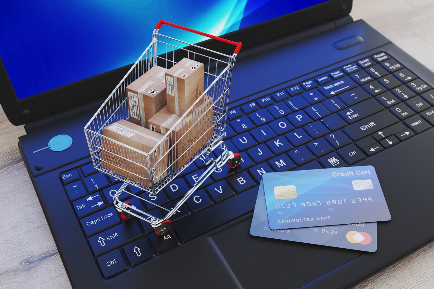 Shopping cart with boxes on laptop keyboard and credit cards, symbolizing ecommerce and online marketing strategies for startups.