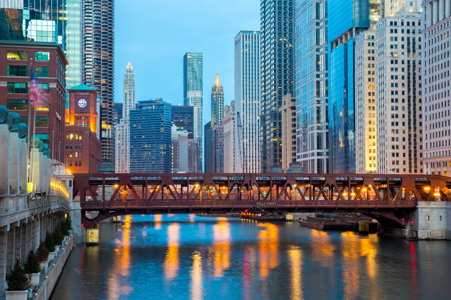 Chicago skyline with illuminated buildings and the Wells Street Bridge over the river, reflecting vibrant colors in the water, symbolizing strong brand identity and presence in urban environments.