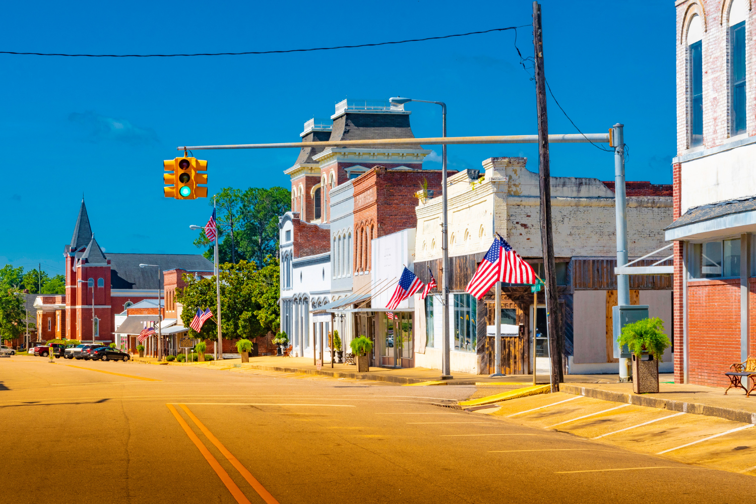 Colorful small-town street scene with historic buildings and American flags, showcasing a vibrant community atmosphere.