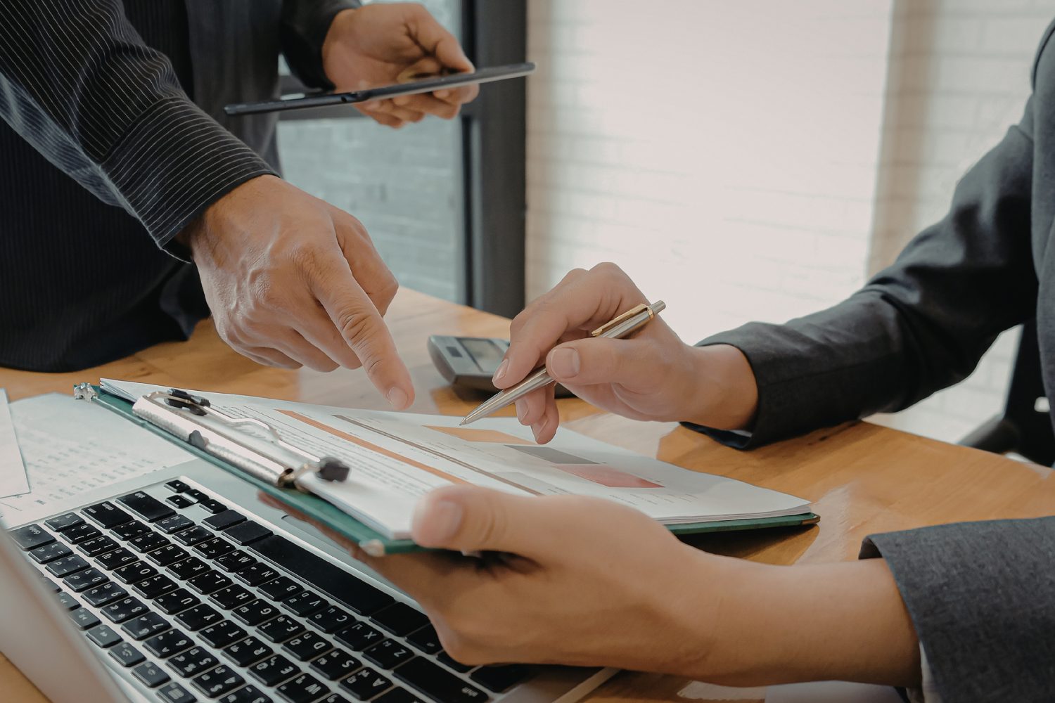 Business professionals discussing marketing strategies over a clipboard with charts and a laptop, emphasizing collaboration for flooring retailers.